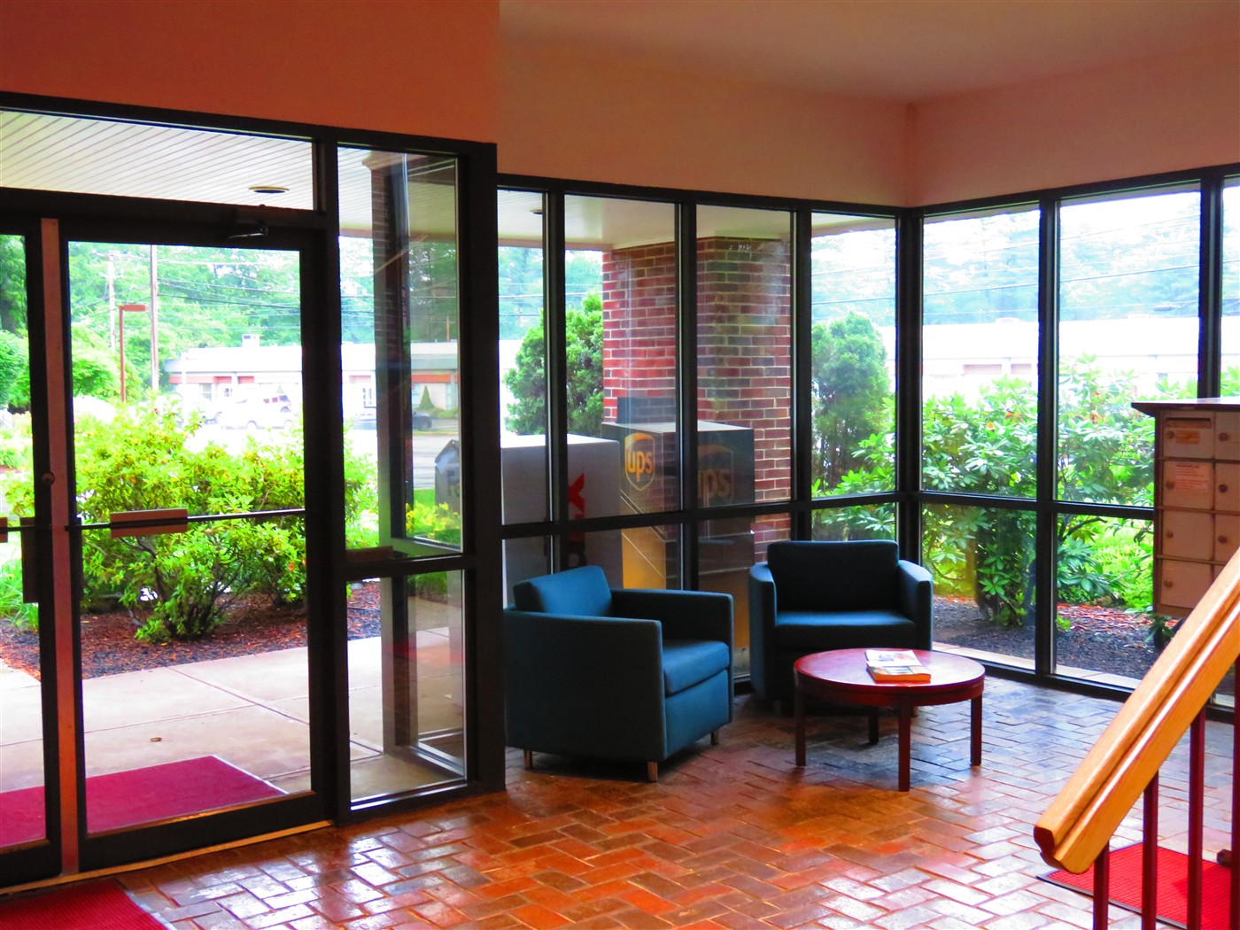 Brick-floored lobby with large windows and two chairs beside the entrance.